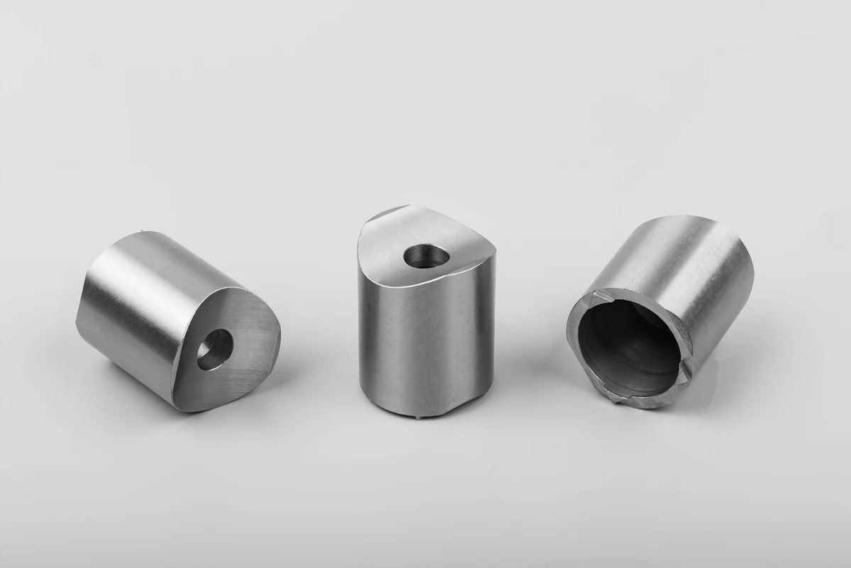 Three CNC turned steel spacers with concentric bores and cross-holes