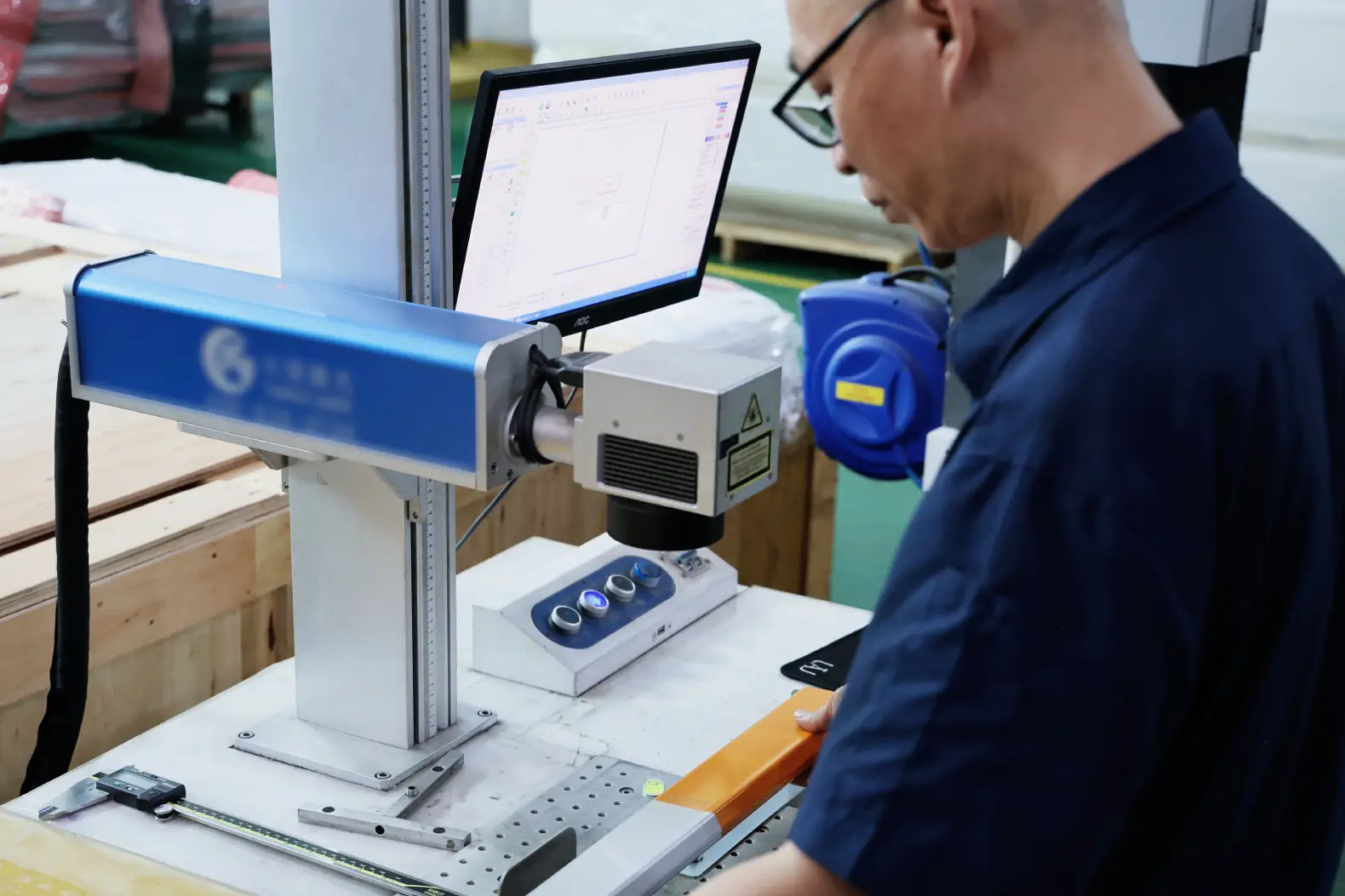 Operator running a fiber laser marking machine on a metal part at Komacut