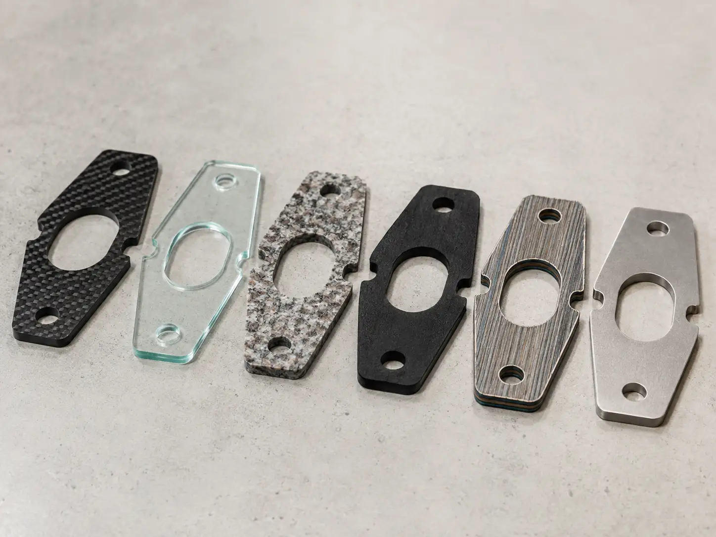 Identical parts waterjet cut from carbon fiber, glass, granite, rubber and steel