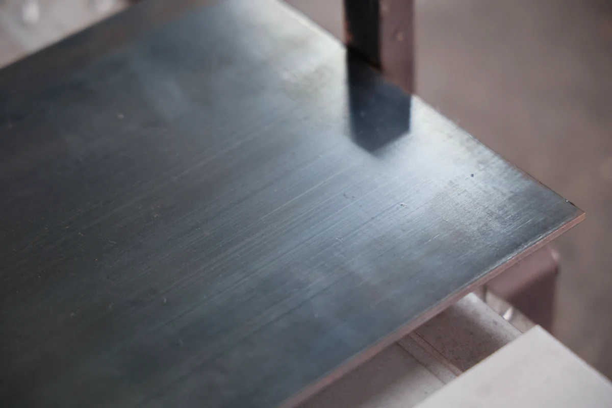 65Mn spring steel sheet stock at Komacut, showing the blued surface finish of hardened, tempered material