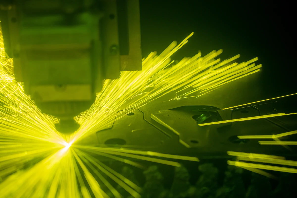 Fiber laser cutting through sheet metal, throwing off sparks