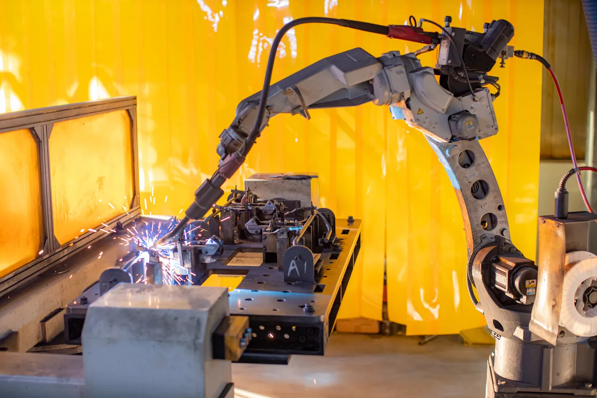Robotic arm welding a sheet metal assembly