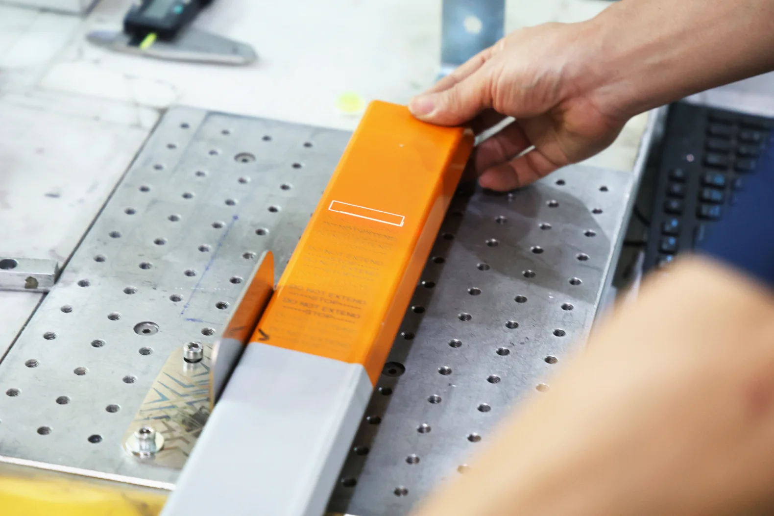 Fiber laser marking safety text through orange powder coating on a metal part