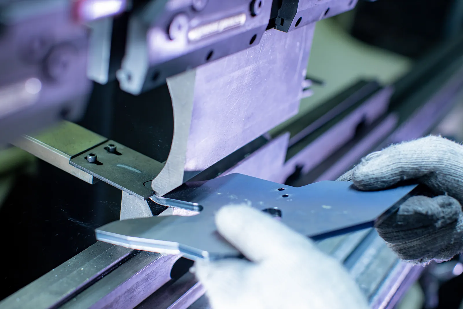 Operator positioning a sheet metal part mid-bend in a press brake