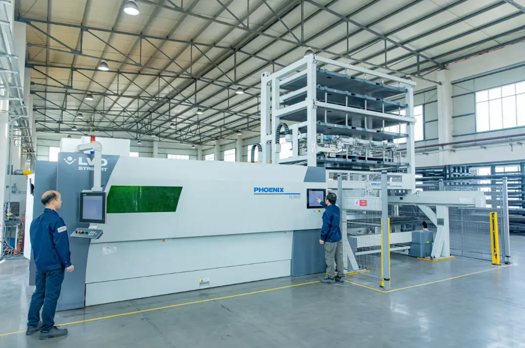Operators running a fiber laser cutting machine with automatic sheet tower at Komacut